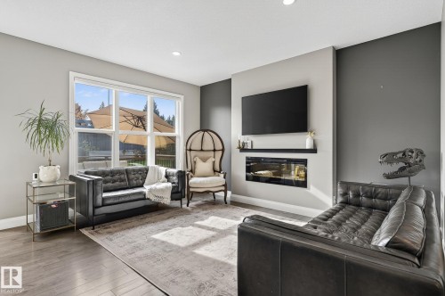 Living space featuring wood-finish flooring and a large window overlooking the outdoor area - 1737 Dumont Crescent, Edmonton, AB - Indoor Photo Showing Living Room With Fireplace