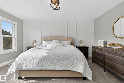 Bedroom featuring a paneled accent wall, a white window, gray carpeting, a bronze ceiling fixture, and light gray painted walls - 1737 Dumont Crescent, Edmonton, AB - Indoor Photo Showing Bedroom