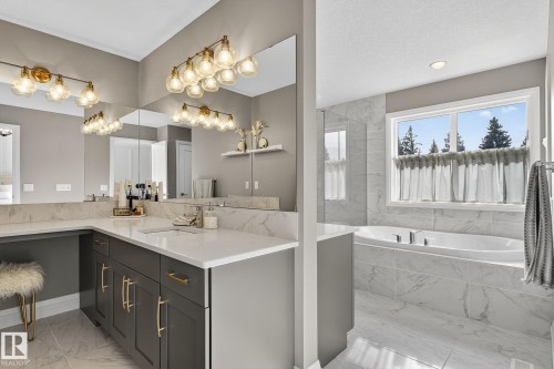 Spacious bathroom featuring an integrated soaking tub, large window, and a vanity with dual sinks - 1737 Dumont Crescent, Edmonton, AB - Indoor Photo Showing Bathroom