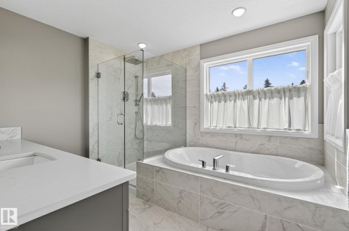 Contemporary bathroom featuring a freestanding soaking tub, glass-enclosed shower, integrated vanity sink, and large format tile surround - 1737 Dumont Crescent, Edmonton, AB - Indoor Photo Showing Bathroom