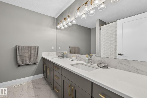 Double vanity featuring integrated sinks, light-toned countertops, and dark cabinetry with gold-tone hardware - 1737 Dumont Crescent, Edmonton, AB - Indoor Photo Showing Bathroom