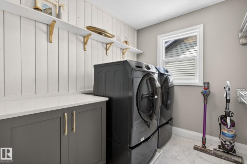 Laundry area featuring shiplap wall accents, built-in shelving with gold-tone brackets, and a counter with shaker-style cabinetry - 1737 Dumont Crescent, Edmonton, AB - Indoor Photo Showing Laundry Room