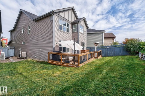 Expansive backyard featuring a manicured lawn, a wooden deck with black metal railings, and a privacy fence - 1737 Dumont Crescent, Edmonton, AB - Outdoor With Deck Patio Veranda With Exterior