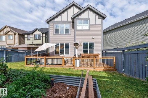 Backyard featuring a wooden deck with black metal balusters, a privacy fence, and a raised garden bed - 1737 Dumont Crescent, Edmonton, AB - Outdoor With Deck Patio Veranda