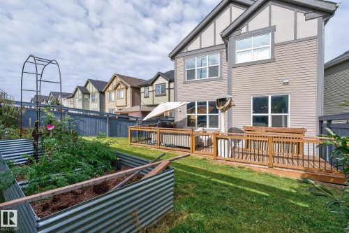 Expansive backyard featuring a manicured lawn, galvanized raised garden beds, and a multi-level wooden deck with black metal railings - 1737 Dumont Crescent, Edmonton, AB - Outdoor With Deck Patio Veranda
