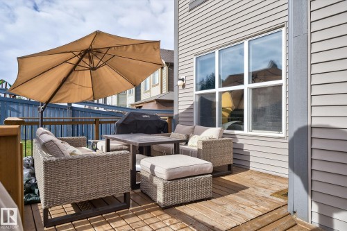 Outdoor wooden deck featuring a slatted surface, perimeter railing with black spindles, and a multi-pane window with white trim - 1737 Dumont Crescent, Edmonton, AB - Outdoor With Deck Patio Veranda With Exterior