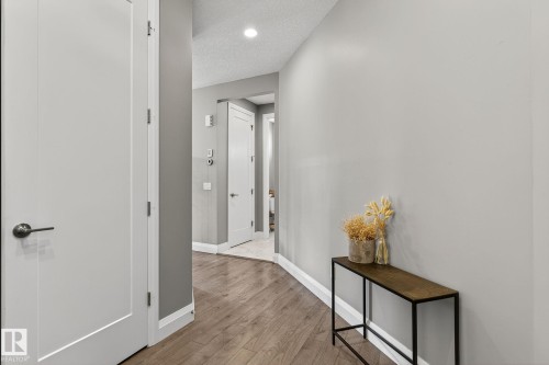 Hallway featuring wood-finish flooring, light gray wall paint, white trim, and white interior doors with dark hardware - 1737 Dumont Crescent, Edmonton, AB - Indoor Photo Showing Other Room