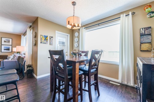 Hardwood-finish flooring extends through this dining area, featuring a tall pub-style dining set with four chairs - 847 Blacklock Way, Edmonton, AB - Indoor Photo Showing Dining Room