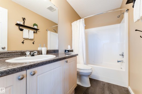 Bathroom featuring a single vanity with a white oval sink, speckled dark countertop, and light wood-finish cabinetry with silver hardware - 847 Blacklock Way, Edmonton, AB - Indoor Photo Showing Bathroom