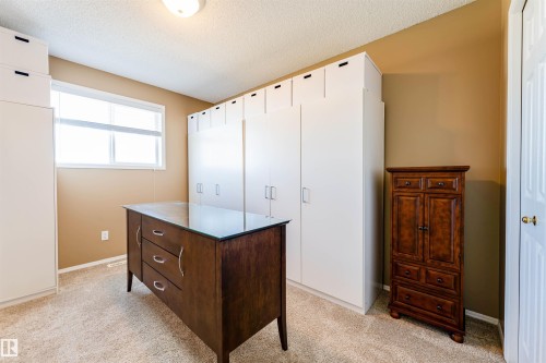 Dedicated room featuring extensive built-in cabinetry, a double-pane window with horizontal blinds, and textured ceiling finish - 847 Blacklock Way, Edmonton, AB - Indoor