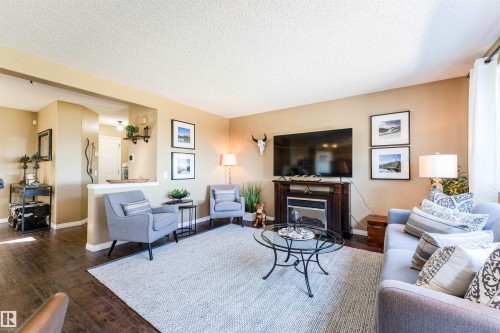 Living area featuring wood-finish flooring, a built-in fireplace with a dark wood mantel, and an open pass-through archway - 847 Blacklock Way, Edmonton, AB - Indoor Photo Showing Living Room