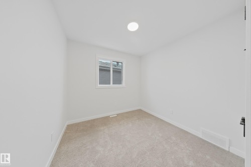 This room features light-colored carpeting, a window with white trim, and a ceiling light fixture - 17 Trill Point(E), Spruce Grove, AB - Indoor Photo Showing Other Room