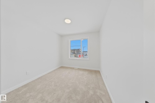 This room features light-colored carpeting, a window providing natural light, and a ceiling-mounted light fixture - 17 Trill Point(E), Spruce Grove, AB - Indoor Photo Showing Other Room