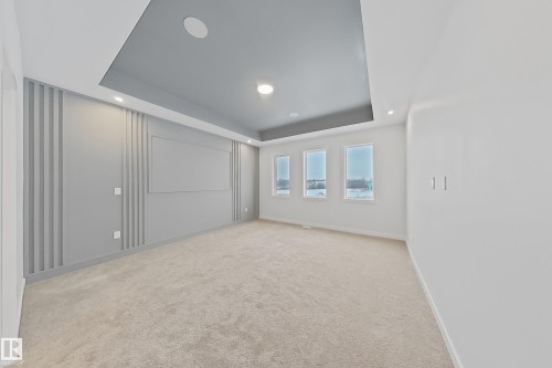 This room features a tray ceiling with recessed lighting, a decorative accent wall with panel detailing, and a carpeted floor - 17 Trill Point(E), Spruce Grove, AB - Indoor Photo Showing Other Room