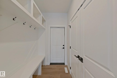 Entryway featuring built-in storage with hooks and shelving, light wood flooring, and white paneled doors - 17 Trill Point(E), Spruce Grove, AB - Indoor Photo Showing Other Room