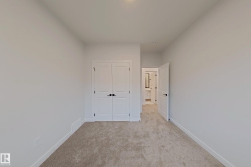 This room features light-colored carpet, white walls, and a closet with double doors - 17 Trill Point(E), Spruce Grove, AB - Indoor Photo Showing Other Room