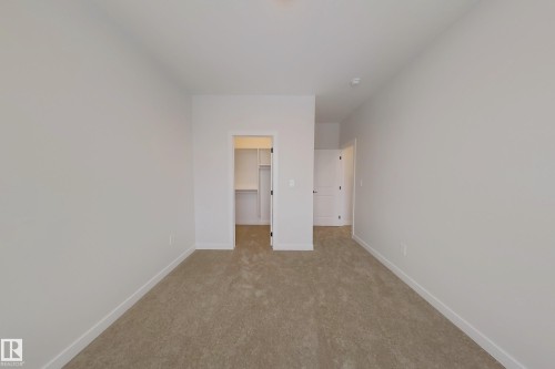 Room featuring light brown carpet, white walls, and an open doorway leading to a closet with shelving - 17 Trill Point(E), Spruce Grove, AB - Indoor Photo Showing Other Room