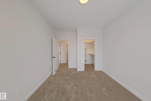 This room features neutral-toned carpet flooring, white walls, and a walk-in closet with shelving - 17 Trill Point(E), Spruce Grove, AB - Indoor Photo Showing Other Room
