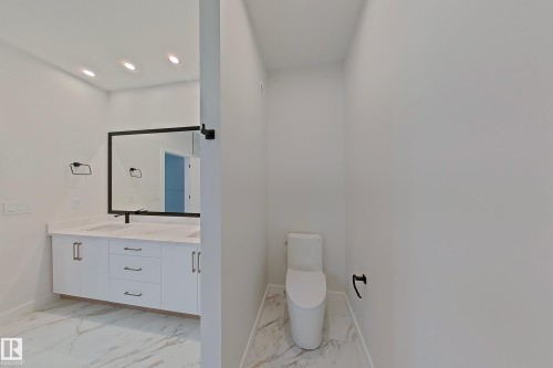 Bathroom featuring a dual vanity with white cabinetry, light-colored countertops, and a large mirror with a dark frame - 17 Trill Point(E), Spruce Grove, AB - Indoor Photo Showing Bathroom