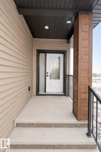 The property features a white paneled entry door with decorative glass inserts, complemented by a black frame and a sidelight - 17 Trill Point(E), Spruce Grove, AB - Outdoor With Exterior
