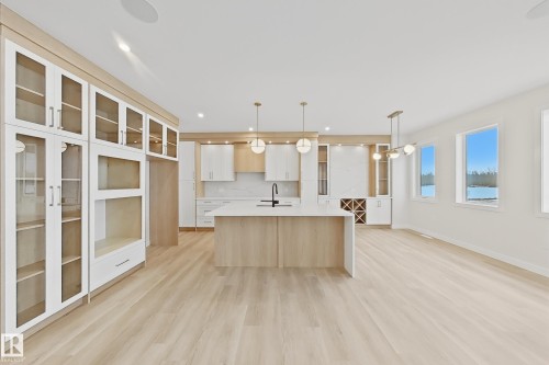 This open-concept kitchen features light wood flooring and a large island with a countertop - 17 Trill Point(E), Spruce Grove, AB - Indoor Photo Showing Kitchen