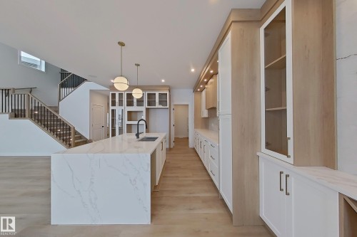 The kitchen features an island with a waterfall countertop, a black kitchen faucet, and pendant lighting - 17 Trill Point(E), Spruce Grove, AB - Indoor