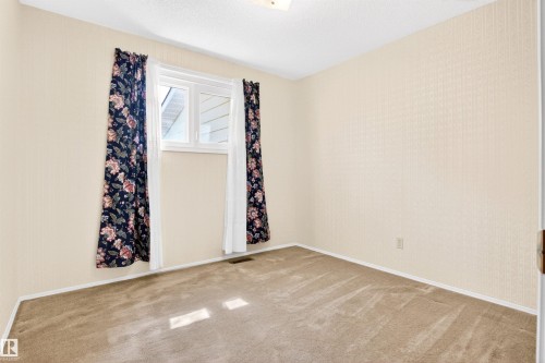 Carpeted room featuring a white-framed window, textured beige walls, and white baseboards - 29 Bristow Crescent, Spruce Grove, AB - Indoor Photo Showing Other Room