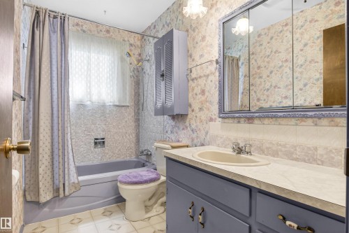 Full bathroom featuring a vanity with an integrated sink, a medicine cabinet with a decorative frame, and a bathtub with a tiled surround - 29 Bristow Crescent, Spruce Grove, AB - Indoor Photo Showing Bathroom