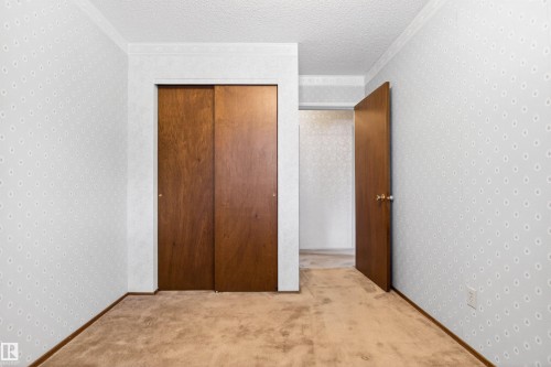 Interior room featuring wood-finish sliding closet doors and a coordinating wood-finish interior door, set against patterned wallpaper - 29 Bristow Crescent, Spruce Grove, AB - Indoor Photo Showing Other Room