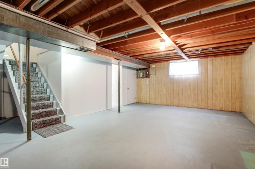 Spacious basement featuring painted concrete flooring, exposed wood beam ceiling, and paneled walls - 29 Bristow Crescent, Spruce Grove, AB - Indoor Photo Showing Basement