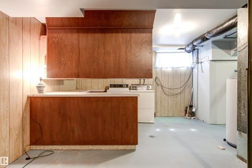 Utility space featuring wood paneling, built-in cabinetry, a counter, and a window - 29 Bristow Crescent, Spruce Grove, AB - Indoor Photo Showing Laundry Room