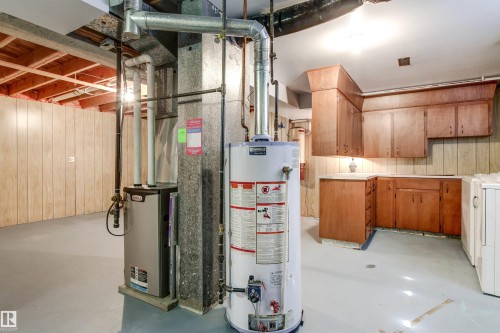 Utility area featuring a water heater, furnace, wood-finish cabinetry, and laminate countertops - 29 Bristow Crescent, Spruce Grove, AB - Indoor Photo Showing Basement