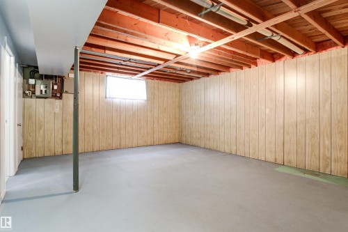 Expansive finished basement space featuring light wood-finish paneling, concrete flooring, exposed ceiling joists, and a utility window - 29 Bristow Crescent, Spruce Grove, AB - Indoor Photo Showing Basement