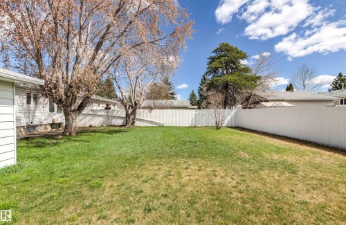 Expansive backyard featuring a manicured lawn, mature deciduous trees, and privacy fencing - 29 Bristow Crescent, Spruce Grove, AB - Outdoor