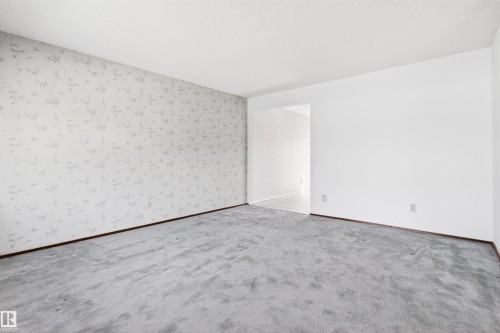 Spacious room with light gray patterned wallpaper, plush gray carpeting, and white painted walls - 29 Bristow Crescent, Spruce Grove, AB - Indoor Photo Showing Other Room