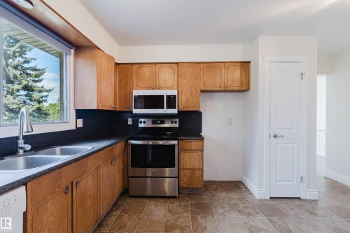 Kitchen featuring wood-finish cabinetry, stainless steel appliances, dual basin sink, and tile flooring - 3752 114 Street, Edmonton, AB - Indoor Photo Showing Kitchen With Double Sink
