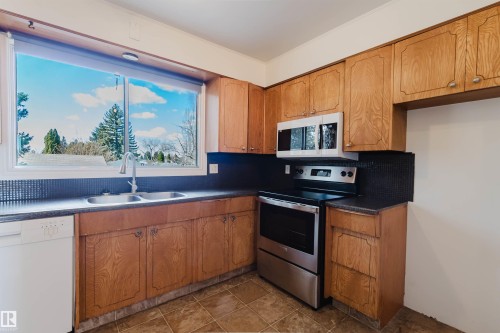Kitchen featuring wood cabinetry, stainless steel appliances, a double basin sink, and ample countertop space - 3752 114 Street, Edmonton, AB - Indoor Photo Showing Kitchen With Double Sink