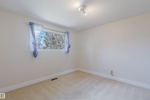 Neutral-toned carpeted room featuring a white-framed window, track lighting, and baseboard trim - 3752 114 Street, Edmonton, AB - Indoor Photo Showing Other Room