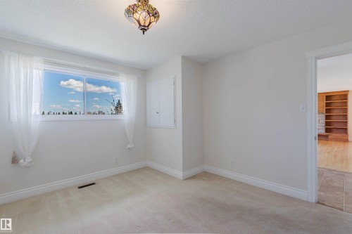 Carpeted room featuring a large window, a decorative ceiling fixture, white baseboards, and a wall-mounted panel - 3752 114 Street, Edmonton, AB - Indoor Photo Showing Other Room