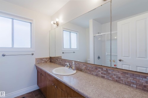 Bathroom featuring an extended vanity with an integrated sink, patterned countertop, and brick-style tile backsplash - 3752 114 Street, Edmonton, AB - Indoor Photo Showing Bathroom