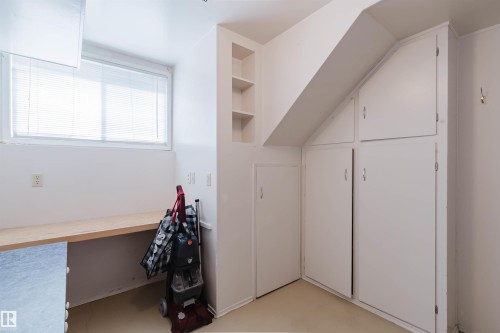 Built-in desk surface with a window, integrated shelving, and multiple storage cabinets - 3752 114 Street, Edmonton, AB - Indoor Photo Showing Other Room