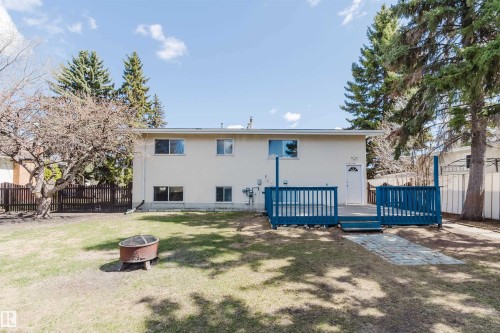 Expansive backyard featuring a multi-level deck with blue railings, a paved stone pathway, a manicured lawn, and mature trees - 3752 114 Street, Edmonton, AB - Outdoor