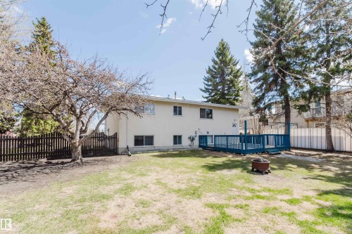 Expansive backyard featuring a large blue wood deck, mature trees, a picket fence, and a stucco exterior - 3752 114 Street, Edmonton, AB - Outdoor With Deck Patio Veranda