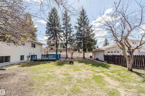 Expansive green space featuring a wood deck, mature trees, and a detached garage with a multi-panel door - 3752 114 Street, Edmonton, AB - Outdoor