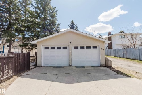 Detached garage featuring two overhead doors with upper window panels, and a concrete driveway - 3752 114 Street, Edmonton, AB - Outdoor