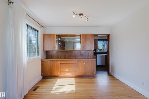 Built-in wood cabinetry with glass-front upper cabinets, wood-finish flooring, and a track lighting fixture - 3752 114 Street, Edmonton, AB - Indoor Photo Showing Kitchen
