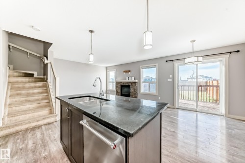 Kitchen island featuring a dark countertop, undermount sink with gooseneck faucet, and integrated stainless steel dishwasher - 1669 Hammond Crescent Nw, Edmonton, AB - Indoor Photo Showing Kitchen With Double Sink