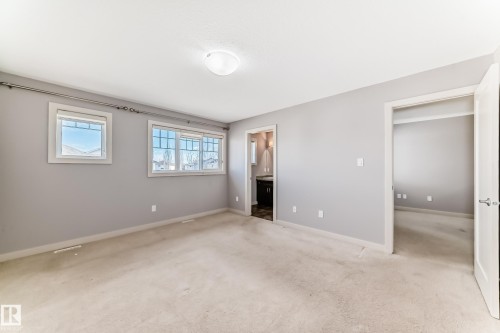 Neutral-toned carpeting and walls, two windows with white trim, and a ceiling-mounted light fixture - 1669 Hammond Crescent Nw, Edmonton, AB - Indoor Photo Showing Other Room