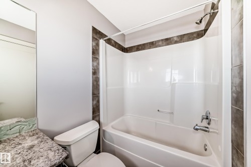 Tub and shower combination featuring dark-toned tiled surround - 1669 Hammond Crescent Nw, Edmonton, AB - Indoor Photo Showing Bathroom