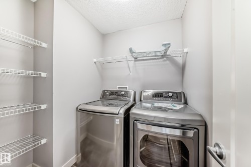 Compact utility area featuring a front-load dryer and a top-load washing machine, both in a stainless steel finish - 1669 Hammond Crescent Nw, Edmonton, AB - Indoor Photo Showing Laundry Room